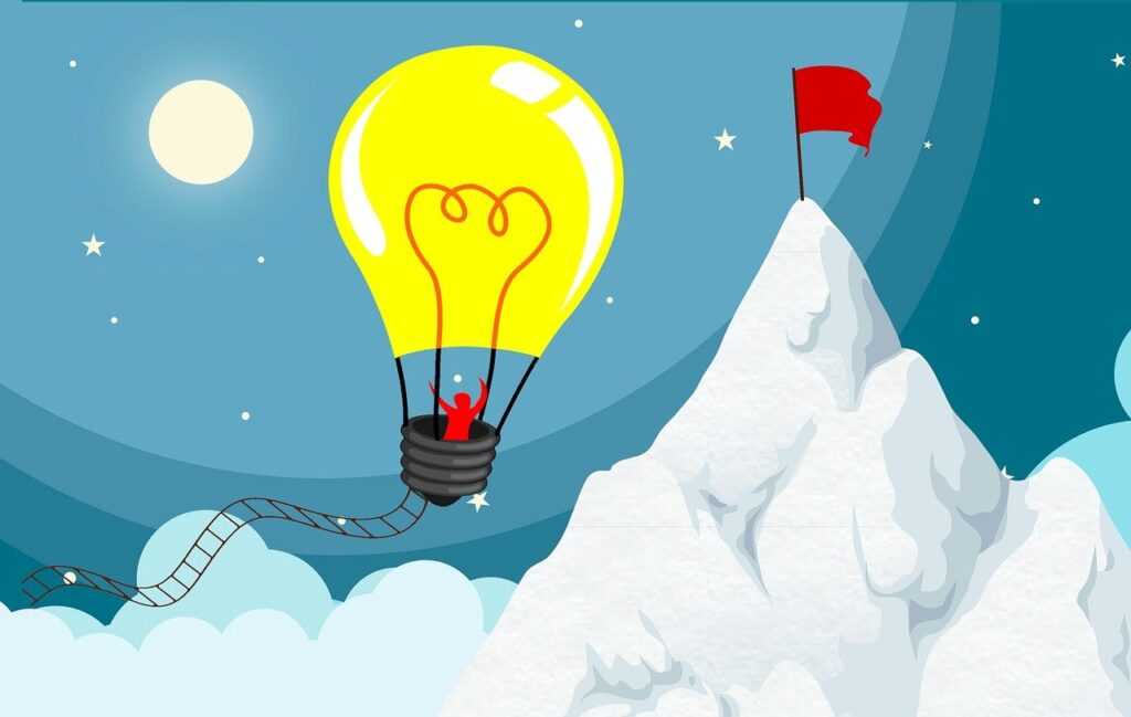 電球の気球に乗っている人が山の頂上へ向かっている
