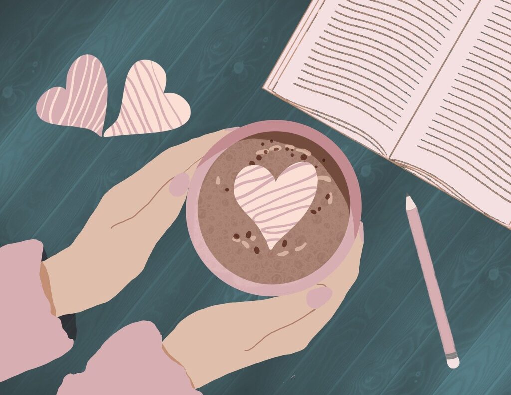 机の上のコーヒーカップを囲む手と本と鉛筆